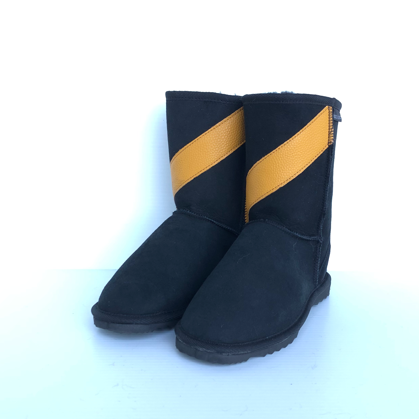 Pair of black Ugg Boots, team coloured with yellow leather style stripe diagonally across front