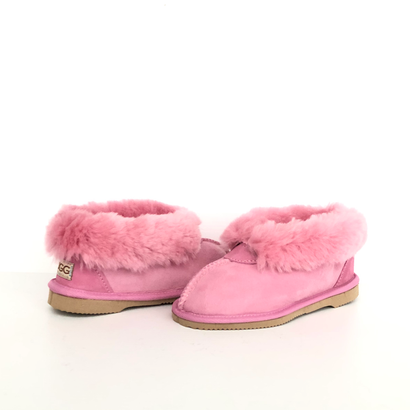 Kid's Ugg Slippers, with sheepskin rolled out at the top in pink