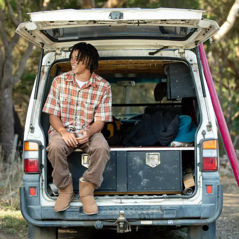 Person sitting in the open trunk of a van with camping gear wearing Australian Made Men's Ugg Boots